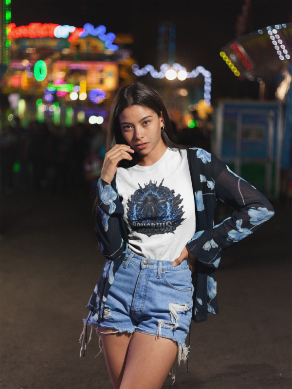Young female model with long straight dark hair wearing high-waisted distressed denim shorts and a blue floral cardigan over a premium white graphic streetwear t-shirt featuring a detailed electric blue Aquarius lightning warrior design by Essentia Collective at an outdoor carnival at night