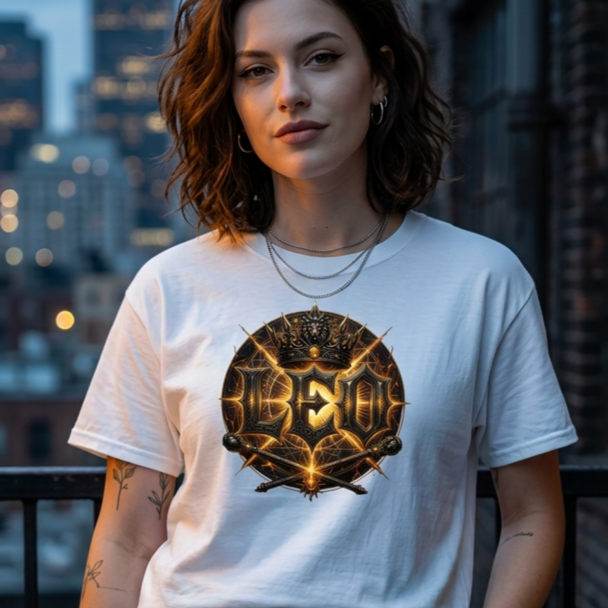 Female model with wavy brown hair wearing a layered silver chain necklace and a premium white graphic streetwear t-shirt featuring a detailed golden Leo crown and scepter design by Essentia Collective on an urban rooftop.