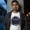 Made Not Given Gothic Streetwear White T-Shirt model standing under a concrete urban bridge overpass at dusk, wearing a dark gray utility jacket open over a white Essentia Collective graphic t-shirt featuring a large chiseled metallic emblem with the words Made Not Given.