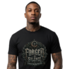 Male model with neck and arm tattoos looking forward against an isolated plain white background, wearing a premium black graphic streetwear t-shirt featuring a highly detailed Forged In Silence metallic emblem.