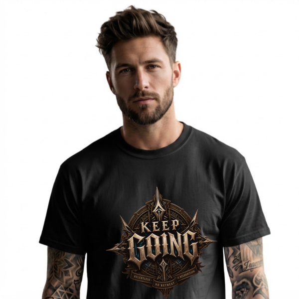 Male model with a groomed beard and tattooed arms looking directly forward against an isolated plain white background, wearing a premium black graphic streetwear t-shirt with a detailed Keep Going shield design by Essentia Collective.