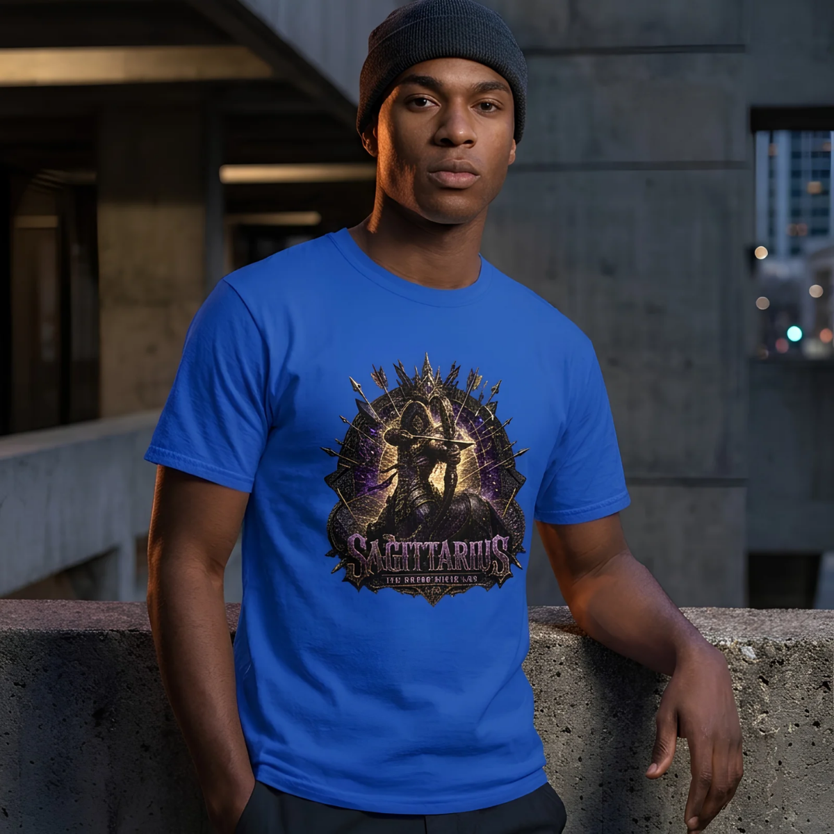 Male model wearing a grey beanie standing against a brutalist concrete structure, wearing a premium royal blue graphic streetwear t-shirt featuring a detailed cosmic Sagittarius archer design by Essentia Collective.