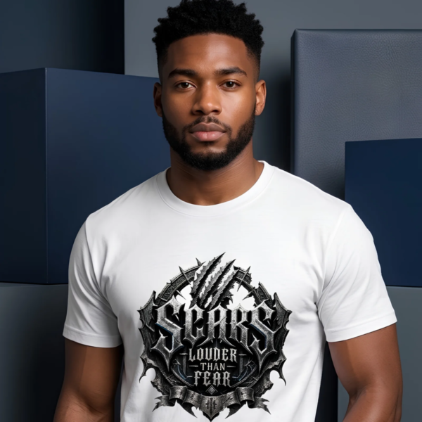 Studio portrait mockup of a male model standing in front of matte navy blue and charcoal gray abstract geometric blocks, wearing a white premium Essentia Collective streetwear t-shirt with a prominent black and silver gothic emblem reading Scars Louder Than Fear.
