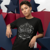 Nothing Wasted Streetwear T-Shirt Black female model with short cropped dark hair leaning against large blue and red geometric star structures, wearing a black premium Essentia Collective graphic streetwear t-shirt with a detailed silver gothic emblem reading Nothing Wasted.