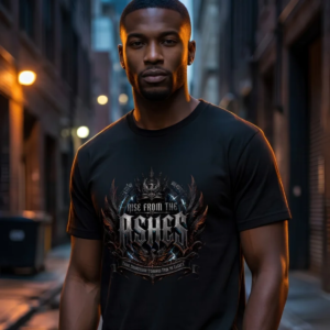 male model in a dark, narrow urban alleyway with warm background lighting, wearing a premium black graphic t-shirt with a metallic gothic phoenix crest reading Rise From The Ashes.