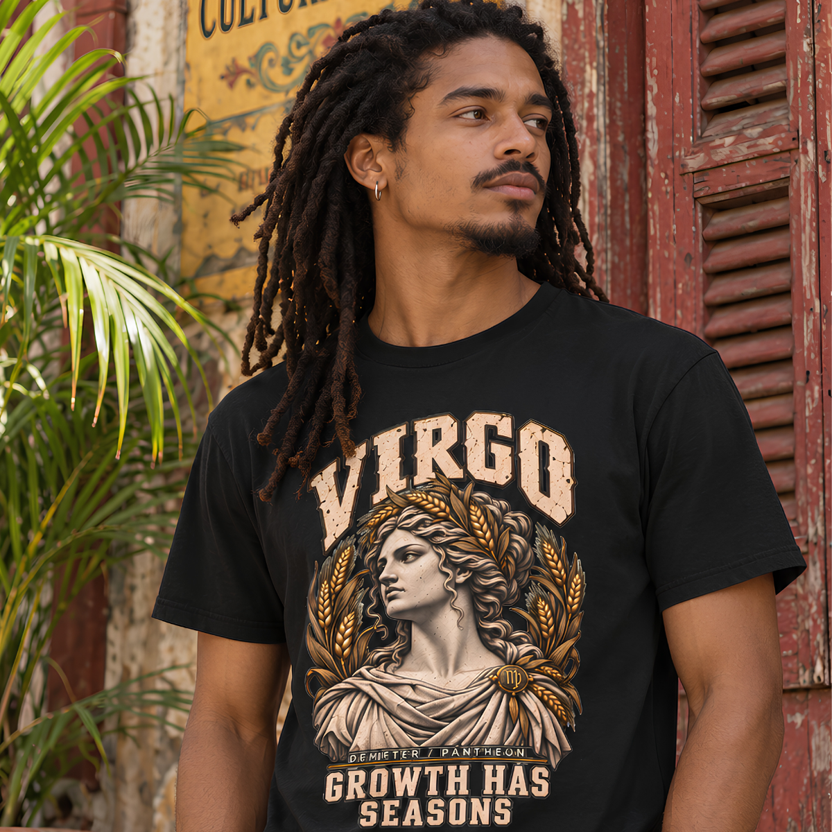 Male model with dreadlocks wearing a black Virgo graphic T-shirt against a rustic red wall.