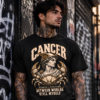 Male model wearing a black Cancer zodiac graphic T-shirt against a dark urban graffiti wall.